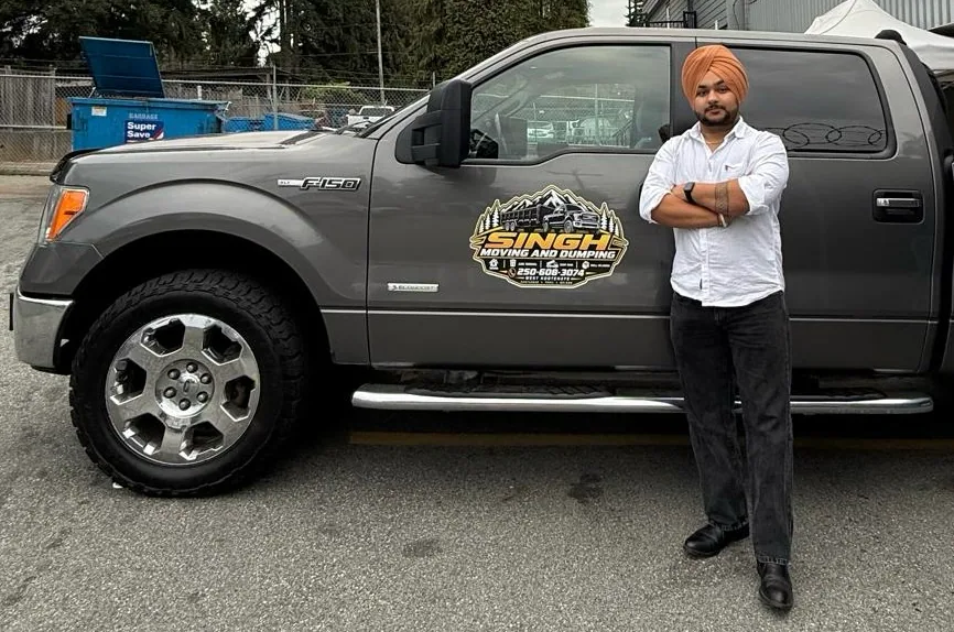Ramandeep Singh standing beside the Singh Moving & Dumping truck