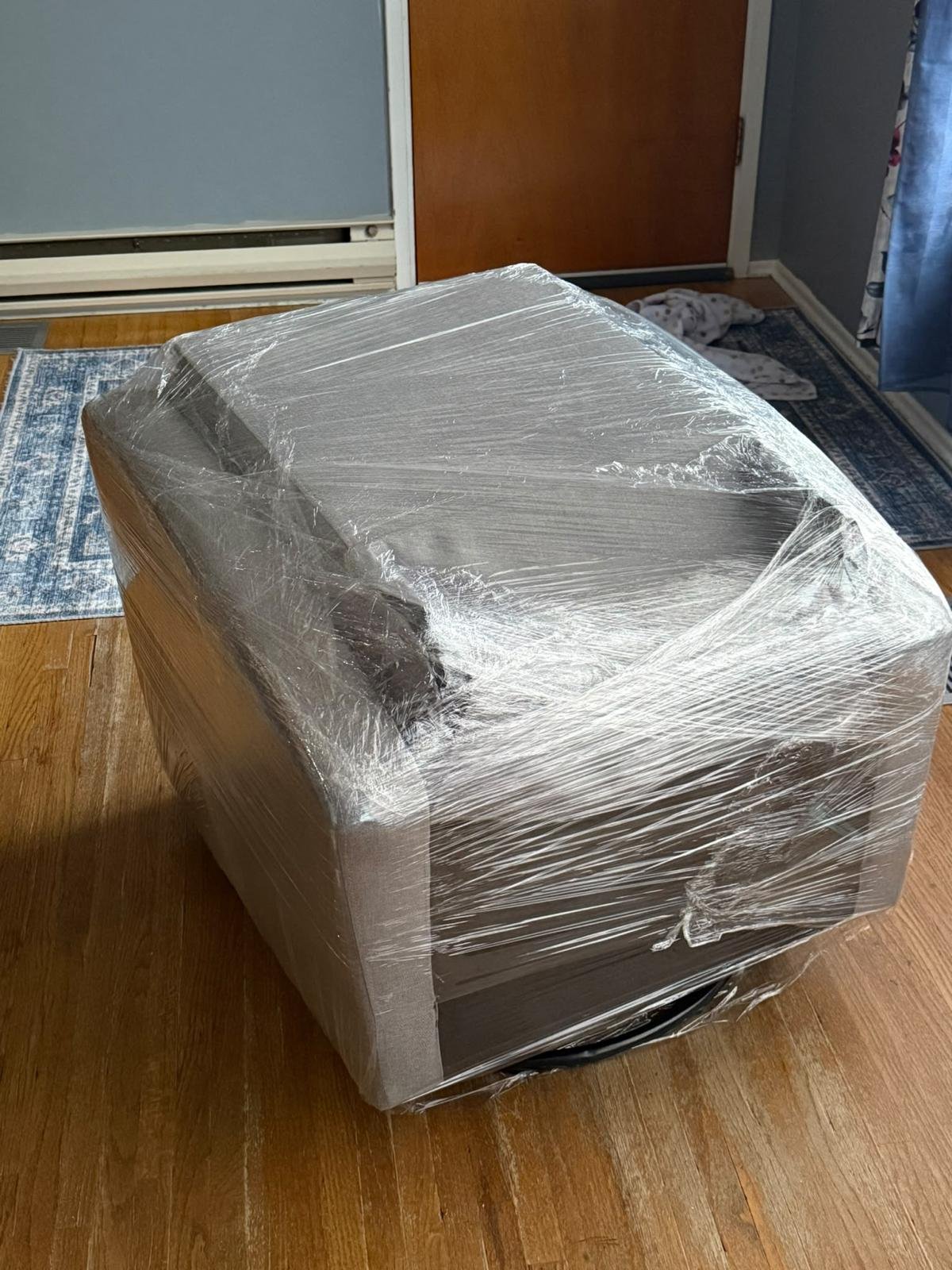 A sofa wrapped with clear stretch film before moving.