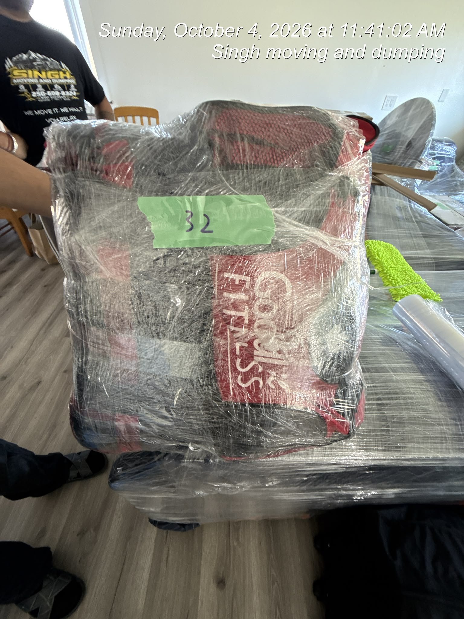 Two movers carrying a sofa with protective wrapping down apartment stairs.